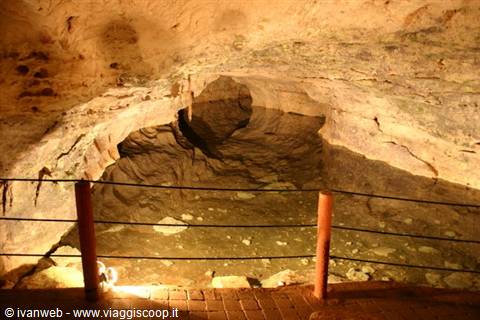Cave with illuminated underground lake, brick walkway and protective railings