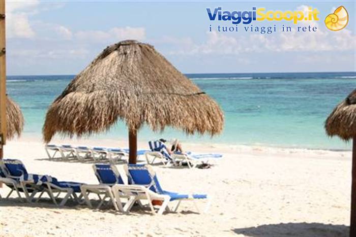White sand beach with straw umbrellas and blue loungers by the turquoise sea