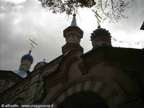 golden crosses and domes above a stone Orthodox church under cloudy sky
