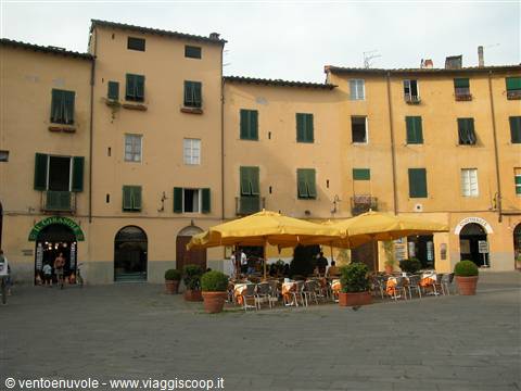 Piazza dell'Anfiteatro in Lucca: café with yellow umbrellas among ochre buildings