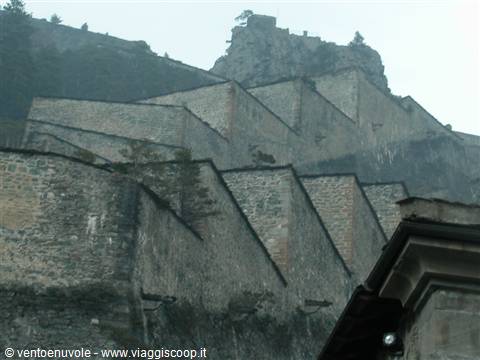 Stone ramparts of Forte di Bard rise in steps through the fog