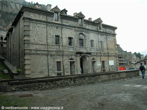 Old stone palace with arched windows and balcony, man walking in square