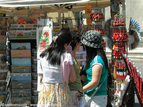 Tourists browsing postcards and souvenirs at a street stall, Florence postcards visible
