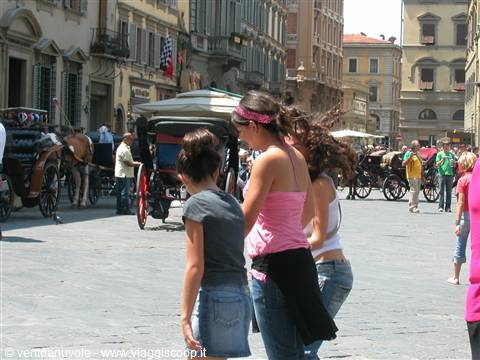 Girls in shorts near horse carriages on a busy Florentine square