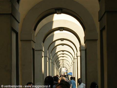 People walking under the stone arches of the Vasari Corridor, Florence