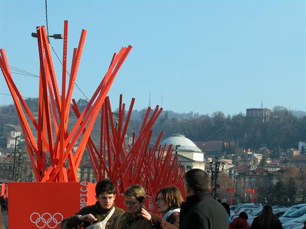 People walk past red Olympic art installations in Turin 2006, Gran Madre church behind