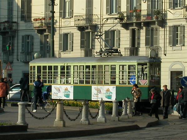 Historic green tram in a Milan square among pedestrians and old buildings