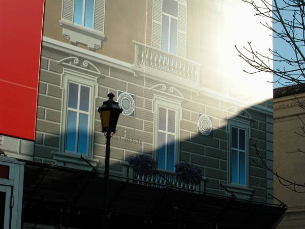 Black street lamp in front of painted facade with classical windows and balconies