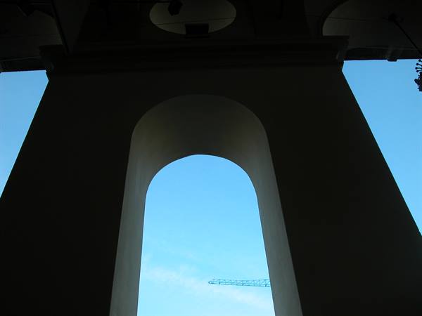 Silhouetted arch against blue sky, a crane in the background