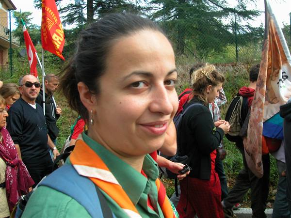 Smiling woman in green and orange scarf among red flags during a walk