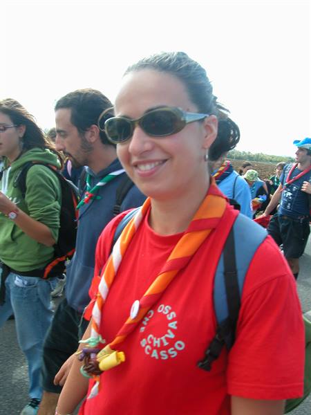 Smiling young scout with orange neckerchief and backpack walking with her group