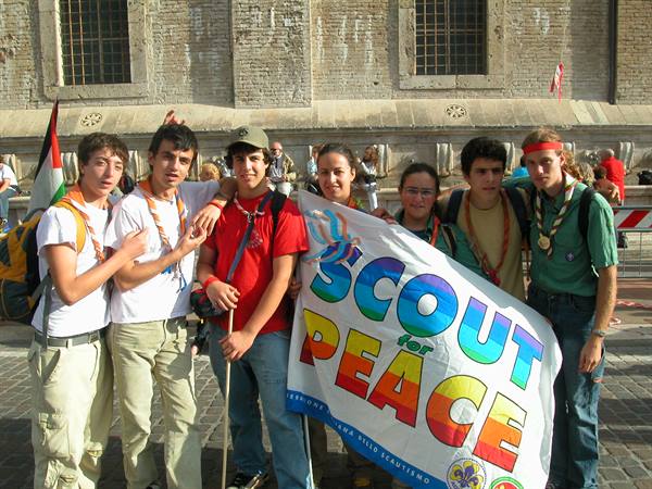Young scouts holding Scout for Peace banner in a square by the fountain
