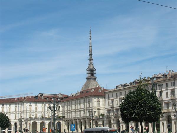 Mole Antonelliana towering over Turin's Piazza Vittorio, pale buildings under blue sky