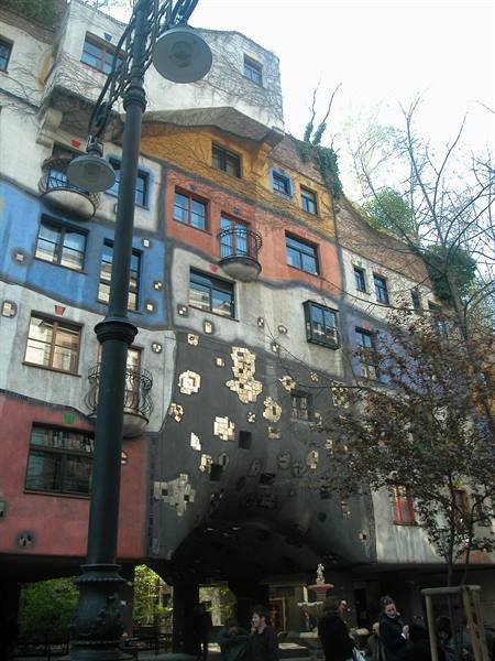 Colorful wavy facade of the Hundertwasserhaus with people at a café
