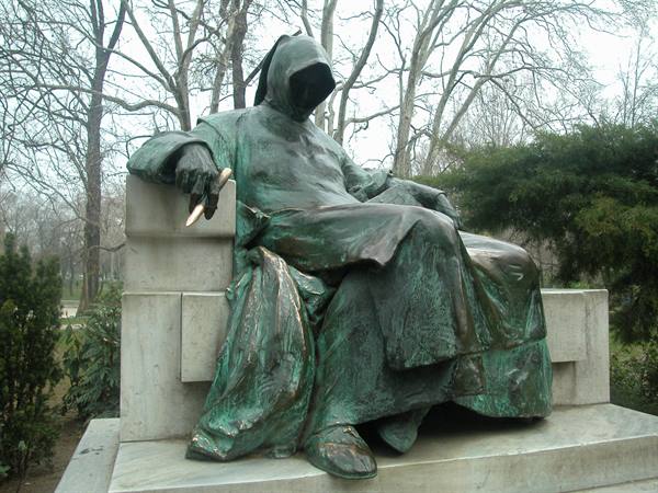 Green bronze statue of a hooded anonymous figure seated on a stone throne