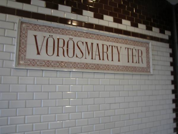 Ceramic sign of Vörösmarty tér metro station on white and brown tiles