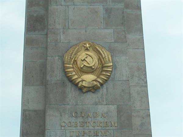 Golden Soviet hammer and sickle emblem on grey stone monument