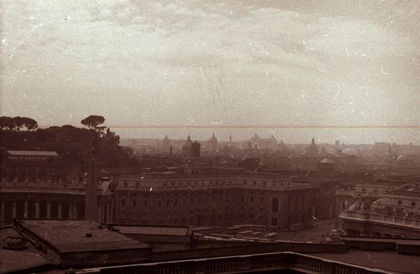 Domes and rooftops of Rome under cloudy sky, vintage sepia photograph