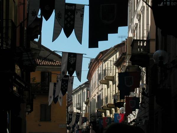 Heraldic banners hung between buildings along a backlit narrow street