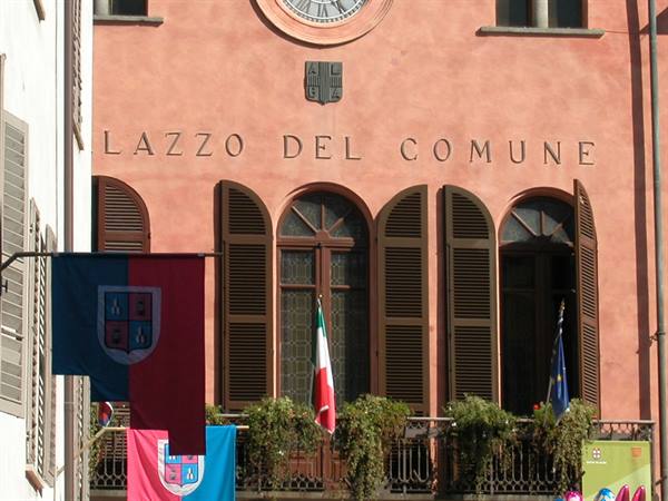 Town hall facade with clock, wooden shutters and fluttering flags