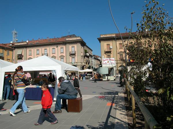 man sitting with a child beside white market tents in the square