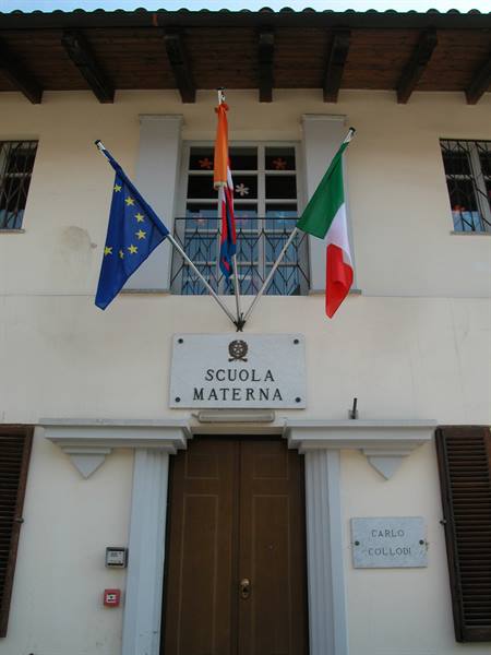 Kindergarten facade with European Union and Italian flags above the wooden door
