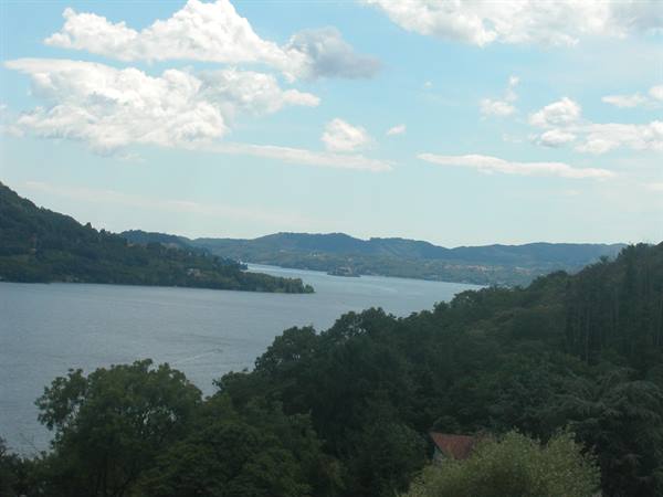 Lake Orta among green hills, white clouds and woods