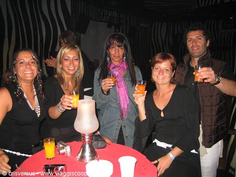 Smiling friends raising drinks at a nightclub table