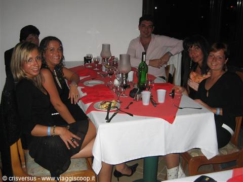 Friends dressed in black smiling around a table set with a red tablecloth