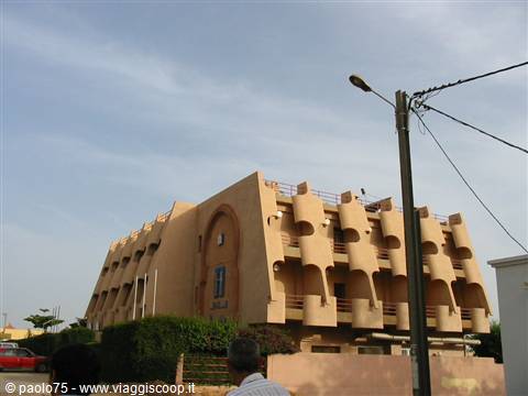 Round-balconied mud-brick building along the street, man seen from behind