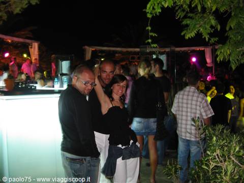 Smiling group of friends at an open-air nightclub, colorful lights