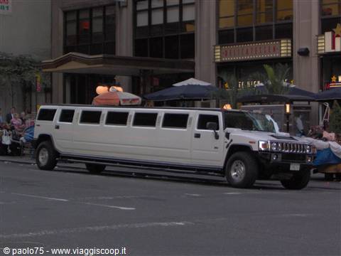 White Hummer limousine parked outside a restaurant with umbrellas in the city
