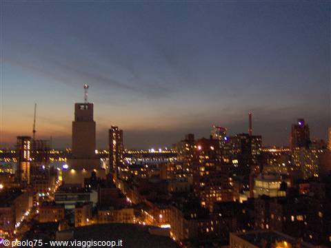 Illuminated New York skyscrapers at dusk, orange sky over the horizon