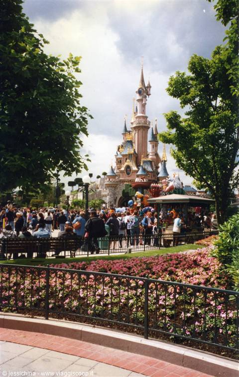 Sleeping Beauty Castle at Disneyland Paris among crowds and flower beds