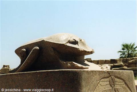Large sandstone scarab statue on a pedestal at Karnak under blue sky