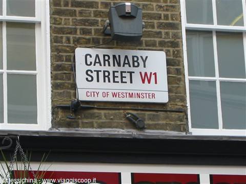 White Carnaby Street W1 sign on brick wall between two windows, London
