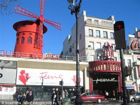 The red windmill of the Moulin Rouge in Paris under blue sky