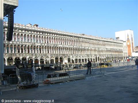 Procuratie arcades in St Mark's Square, Venice, with bell tower under blue sky