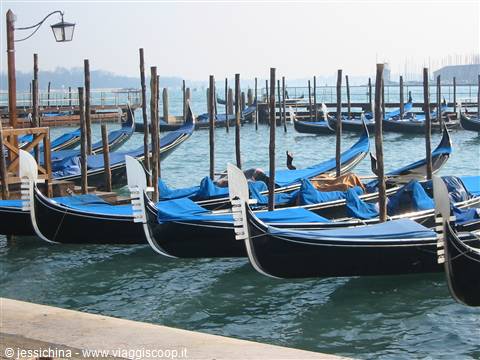 Black gondolas covered with blue tarps moored in Venice