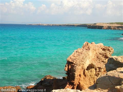 Ochre limestone rocks by turquoise sea, sunny rocky coastline ahead
