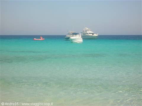 White boats and red dinghy anchored on clear turquoise sea