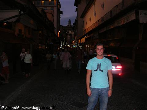 Smiling guy on a crowded pedestrian street in Florence at dusk