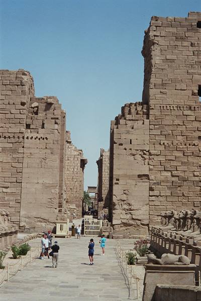 Tourists walk between stone walls at Karnak temple