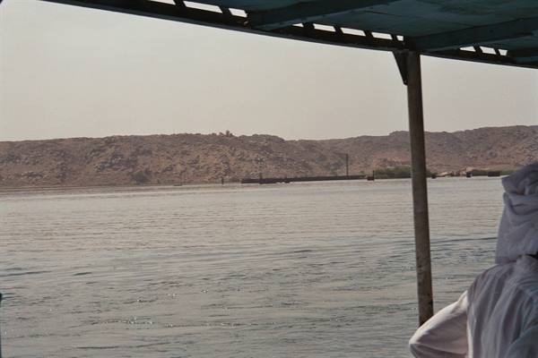 Under a boat canopy, the Nile with desert banks and figures in white