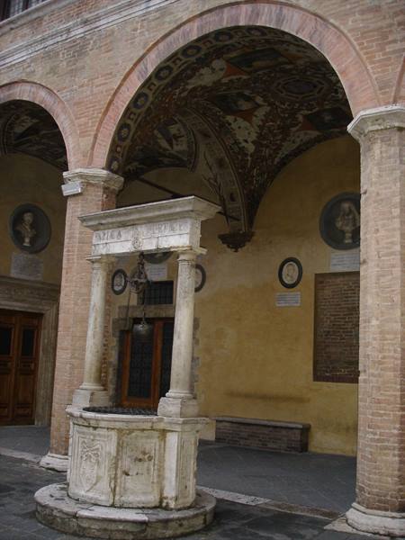 Marble well under the frescoed loggia of the palace, Siena