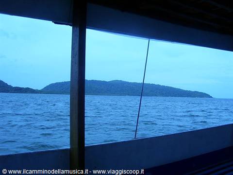 Forested island seen from a boat deck on grey-blue sea