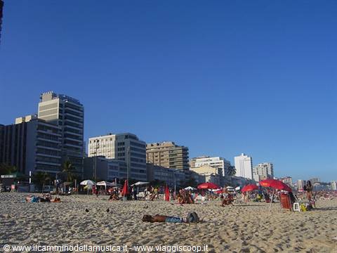 Urban beach with red umbrellas, sunbathers on sand and high-rise buildings, Copacabana