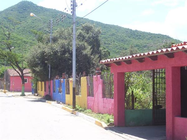 Colorful wall along the street, pink house with tile roof, green hill