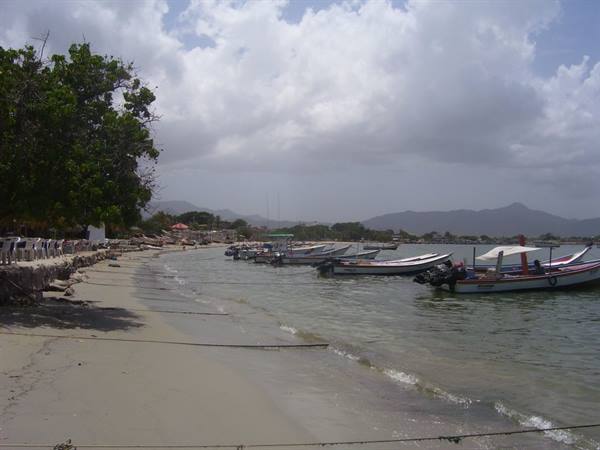 Fishing boats moored along the sandy shore, cloudy sky and mountains