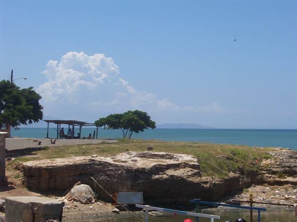 Limestone rock by the shore, wooden shelter and tree under white clouds
